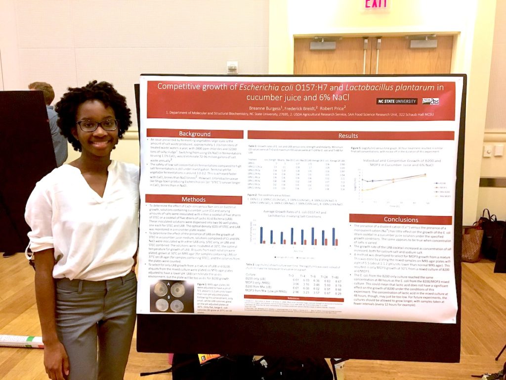 Burgess stand by her bacterial studies presentation poster.