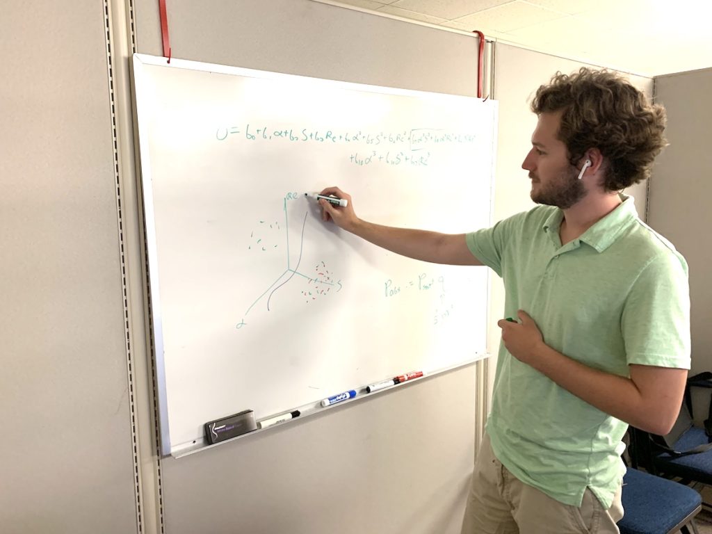 Nate writes statistical equations on a whiteboard.