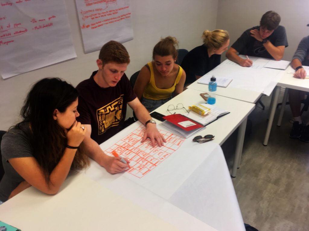 Students sit at a table working on a project.