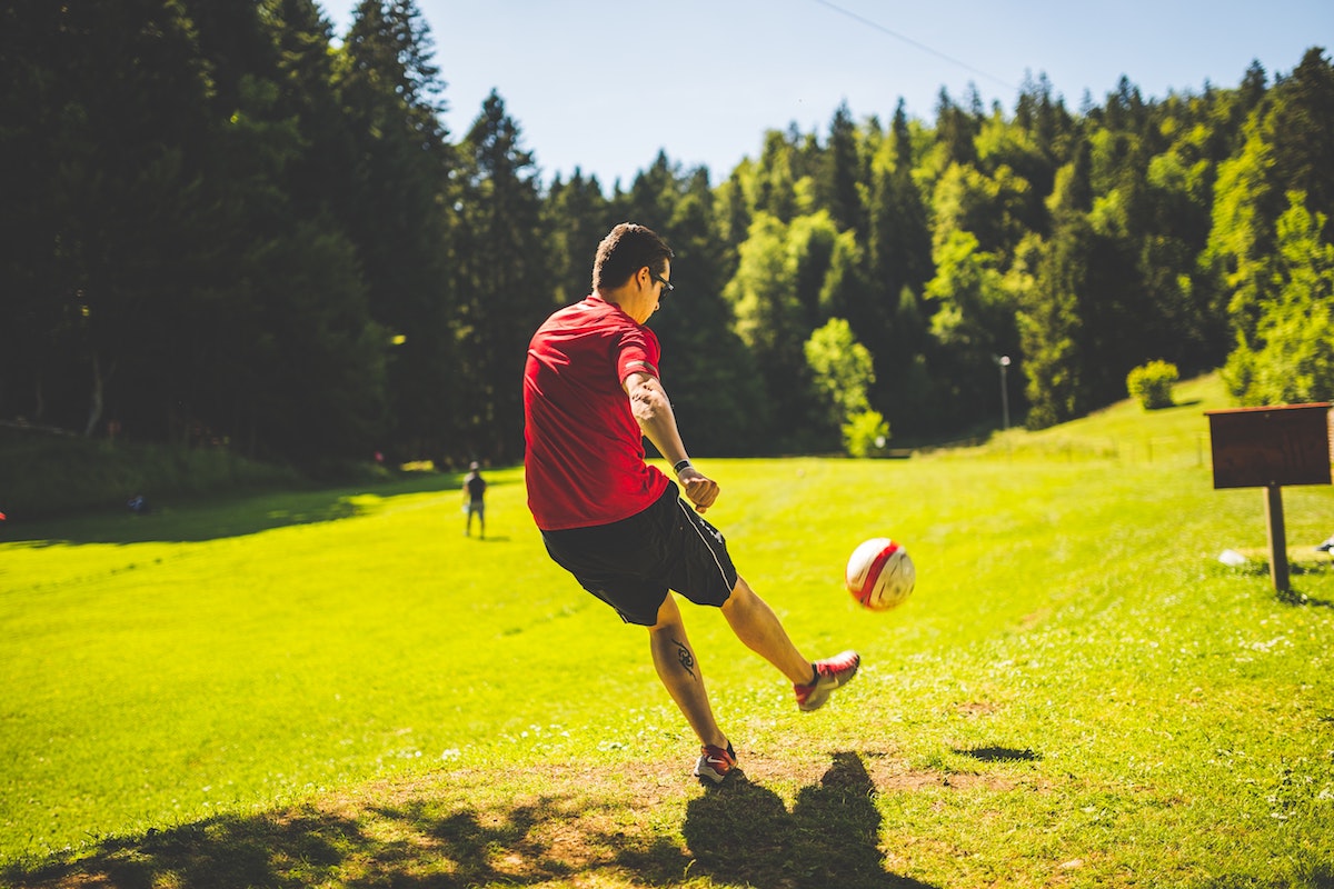 Guy kicks a soccer ball in park