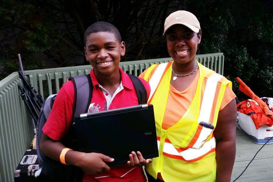 Angela Caraway presents a laptop to a student as part of the Caraway Foundation's 2014 Back to School Bash