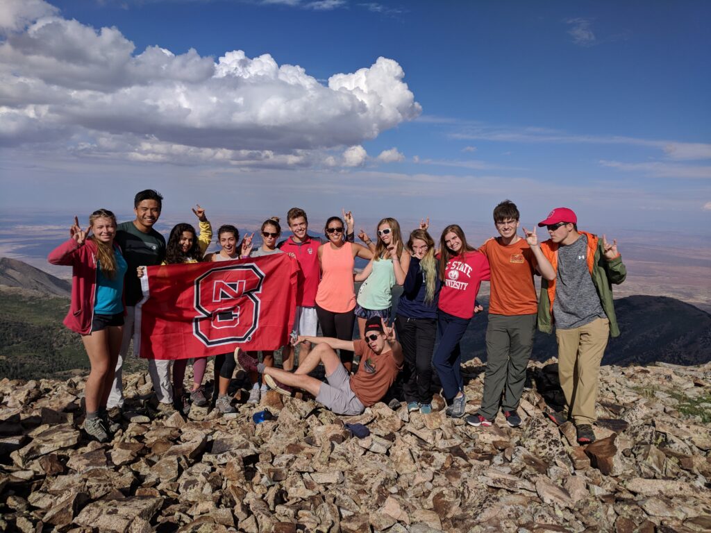 Students hold the NC State banner on a scenic overlook