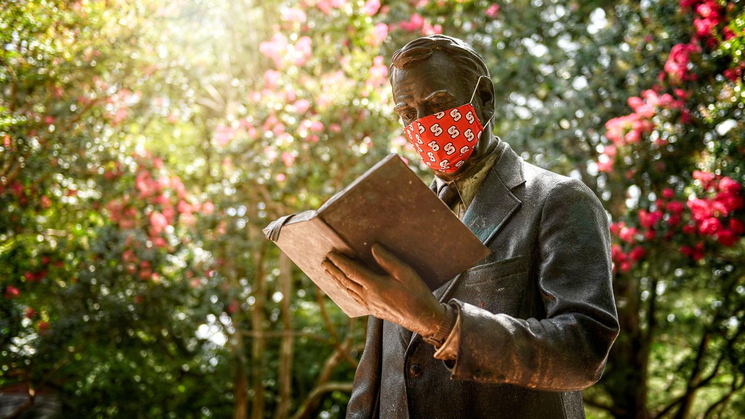 Strolling professor statue wearing a mask
