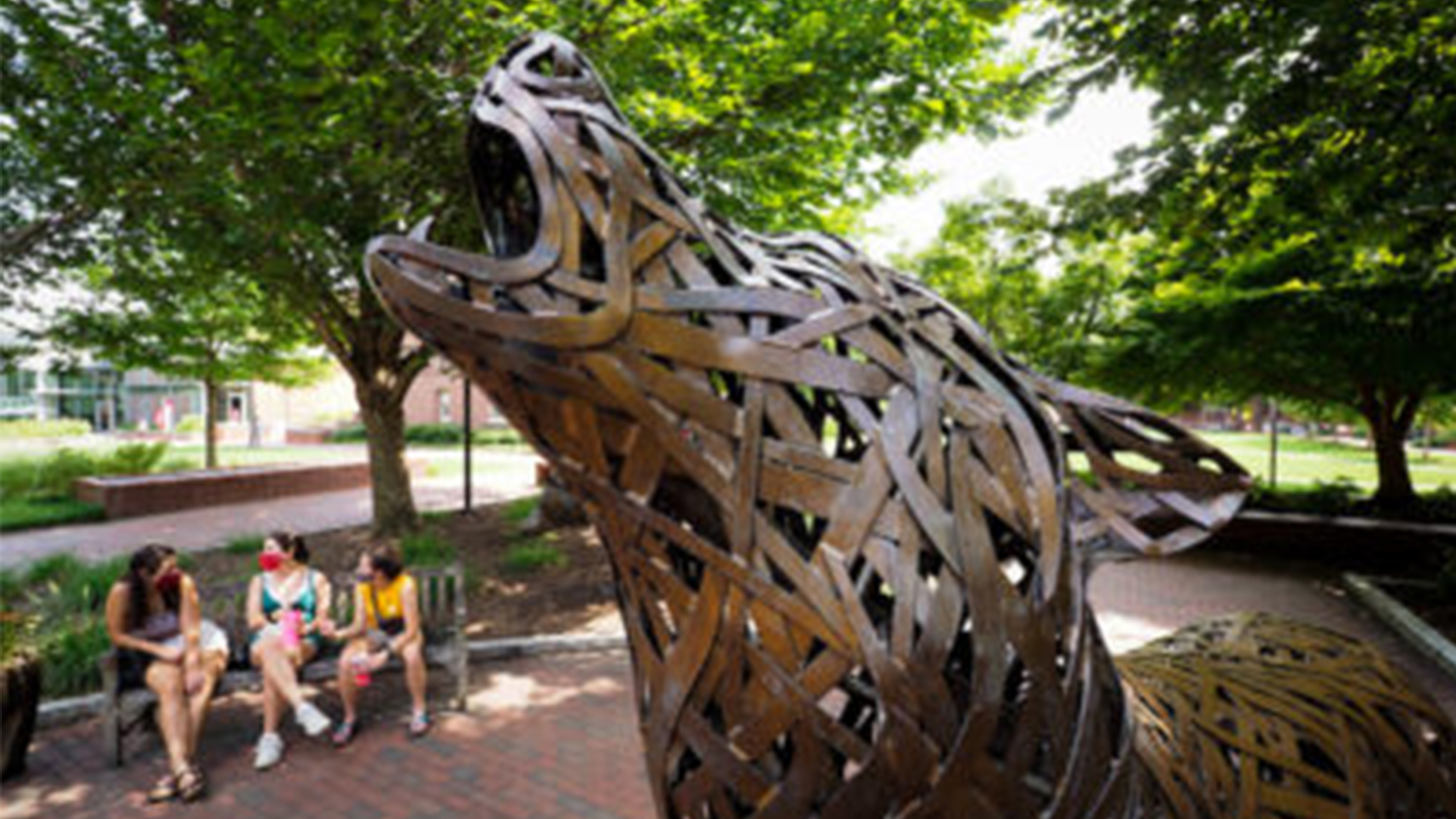 Howling wolf statue with students in the background