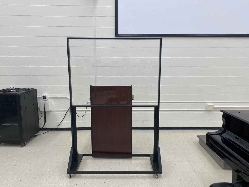 Plexiglass barrier around a podium in a music classroom