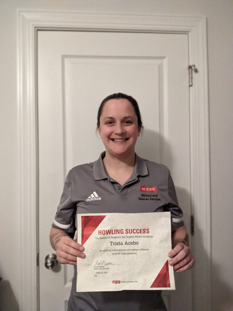 Trista Acebo, holding a certificate in front of a white door