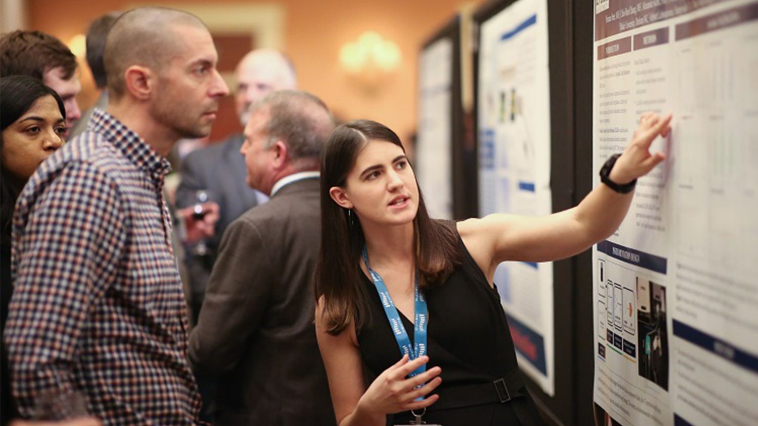 A student presents research on a poster at a conference