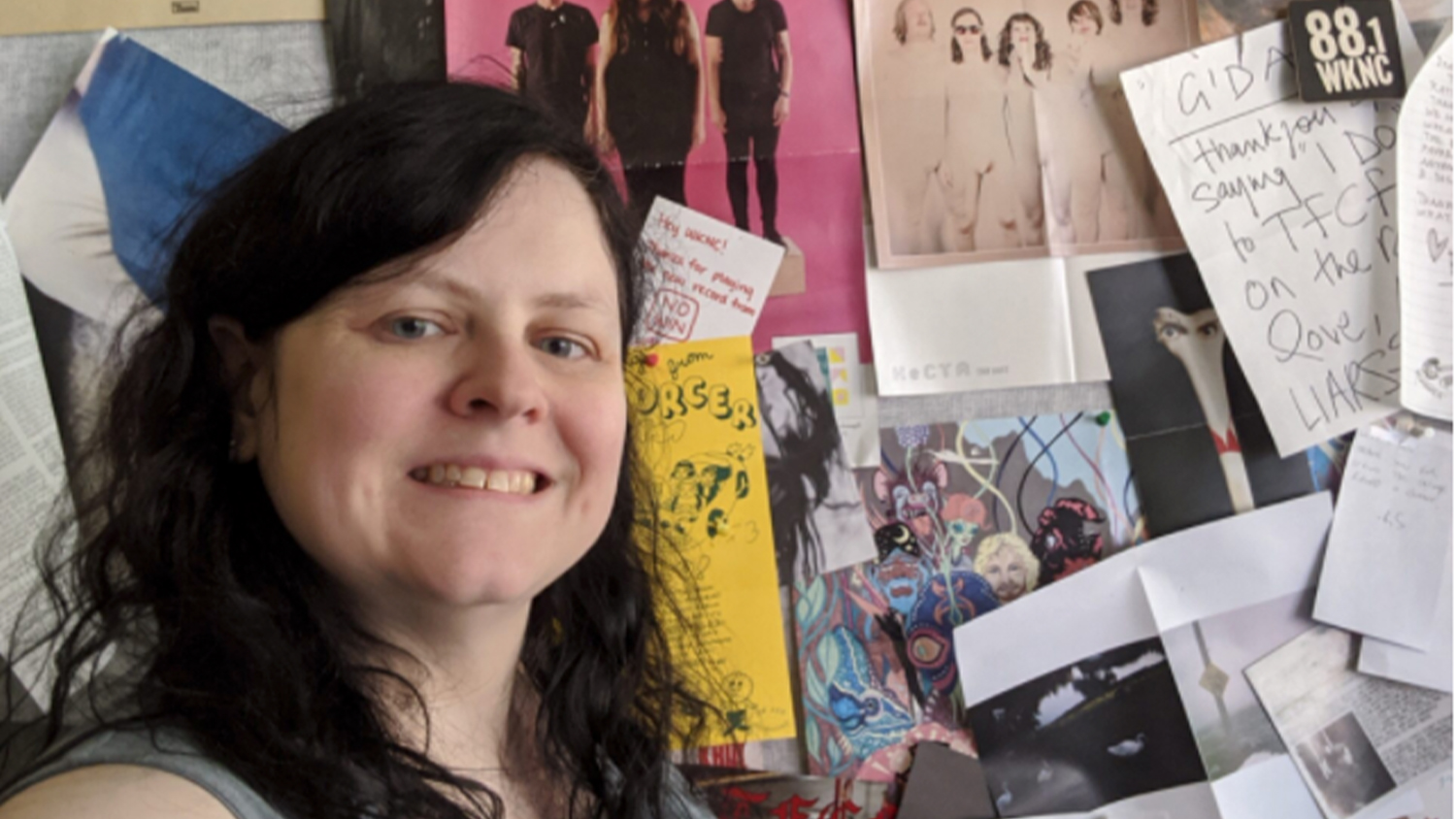 Jamie Lynn Gilbert in front of a wall full of music-related posters