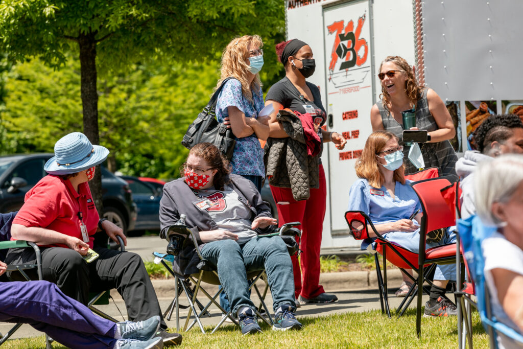 Student Health employees listen to music and talk on the lawn