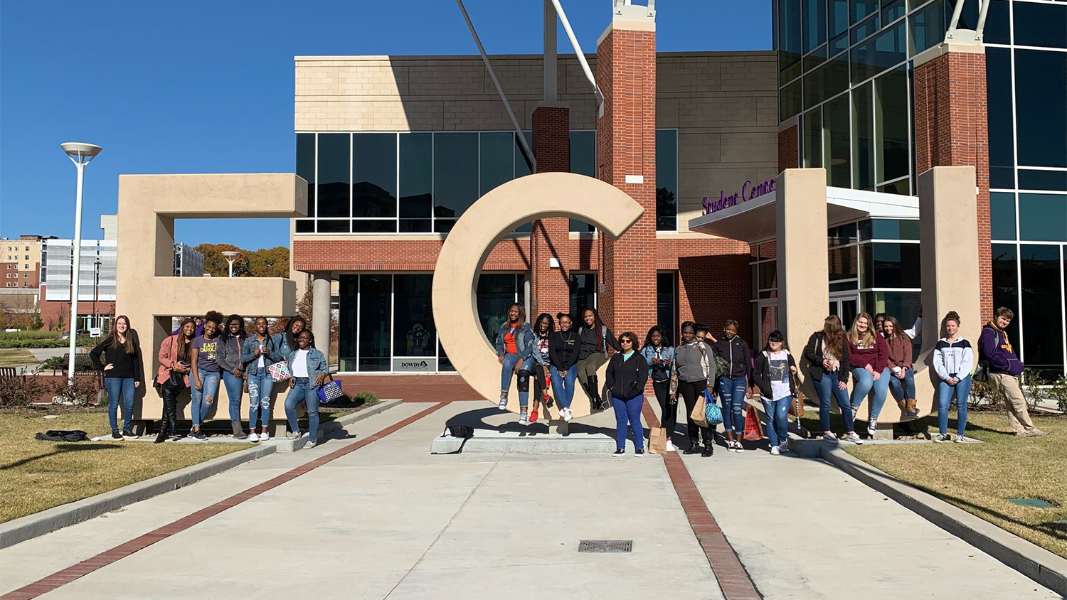 A large group of students in front of large concrete ECU letters on ECU campus