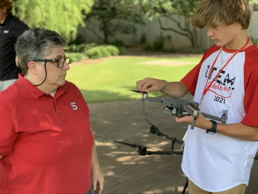 Justine Hollingshead helps a student configure their drone outside on the Court of Carolina 