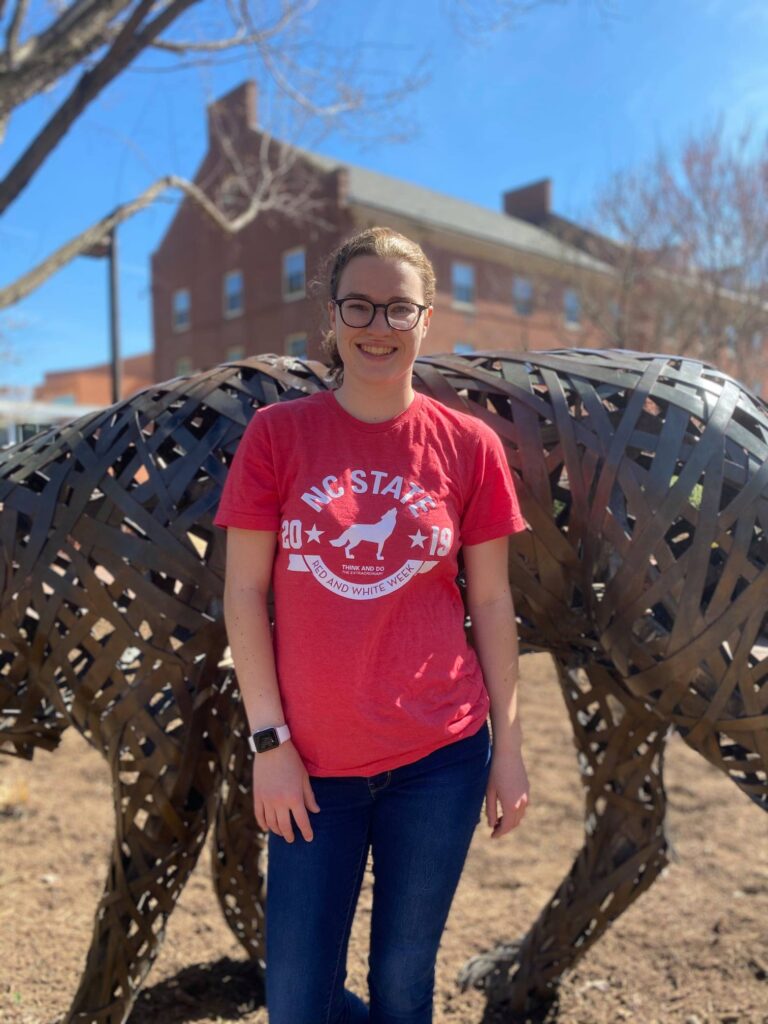 Lauren Bradley in front of a wolf statue in Wolf Plaza