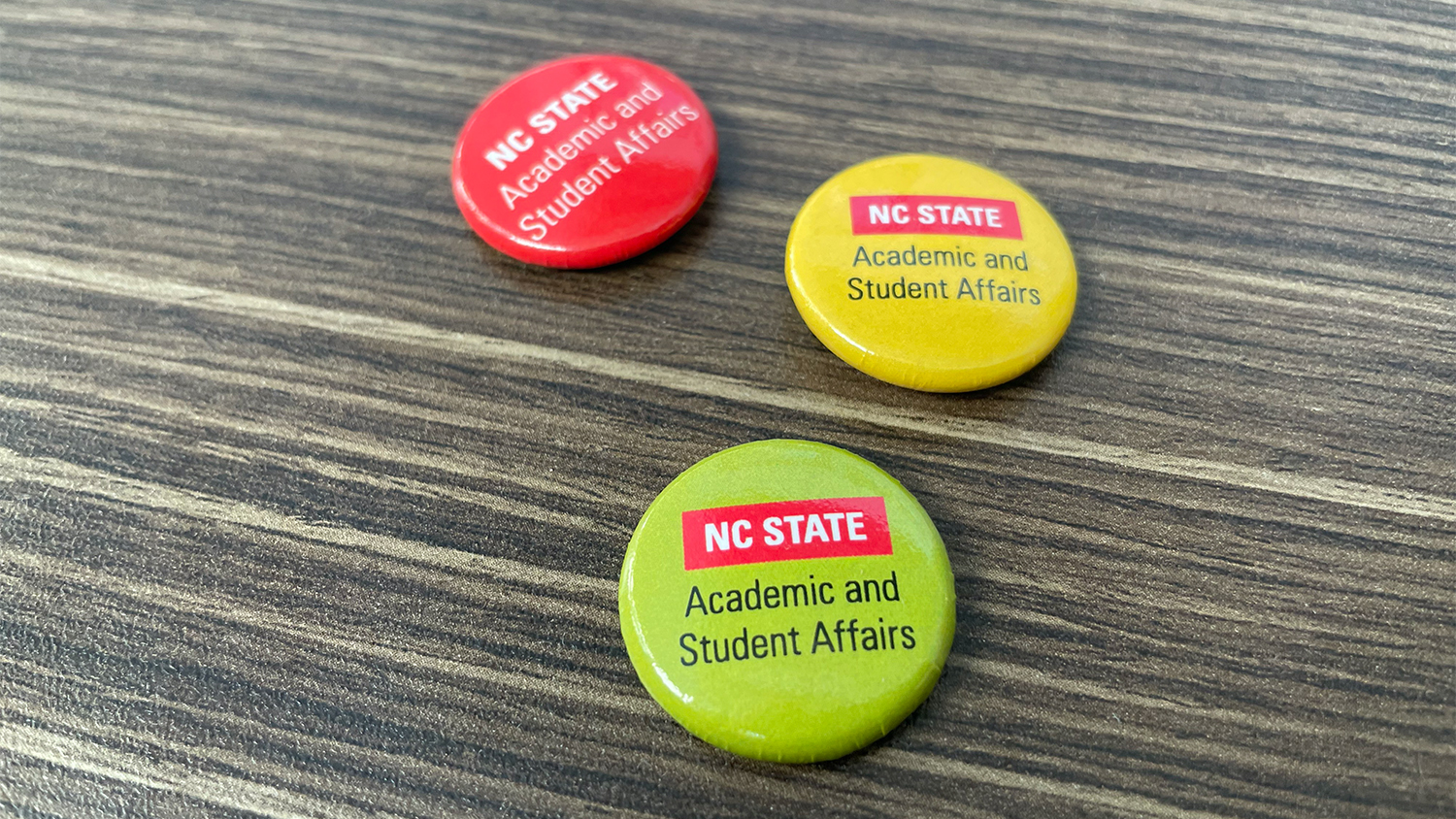 Red, yellow and green buttons with the NC State Academic and Student Affairs logo on them