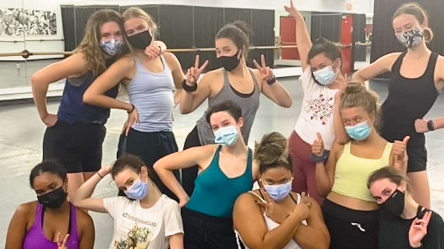 A group of dance students pose and make wolfie signs during the residency weekend