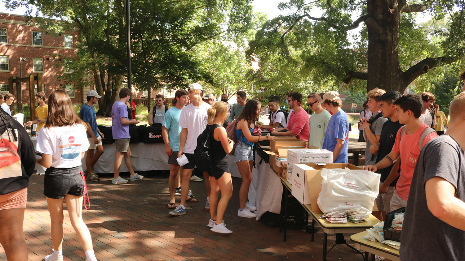 Students wait in line for food at tables during a Grillin and Chillin event