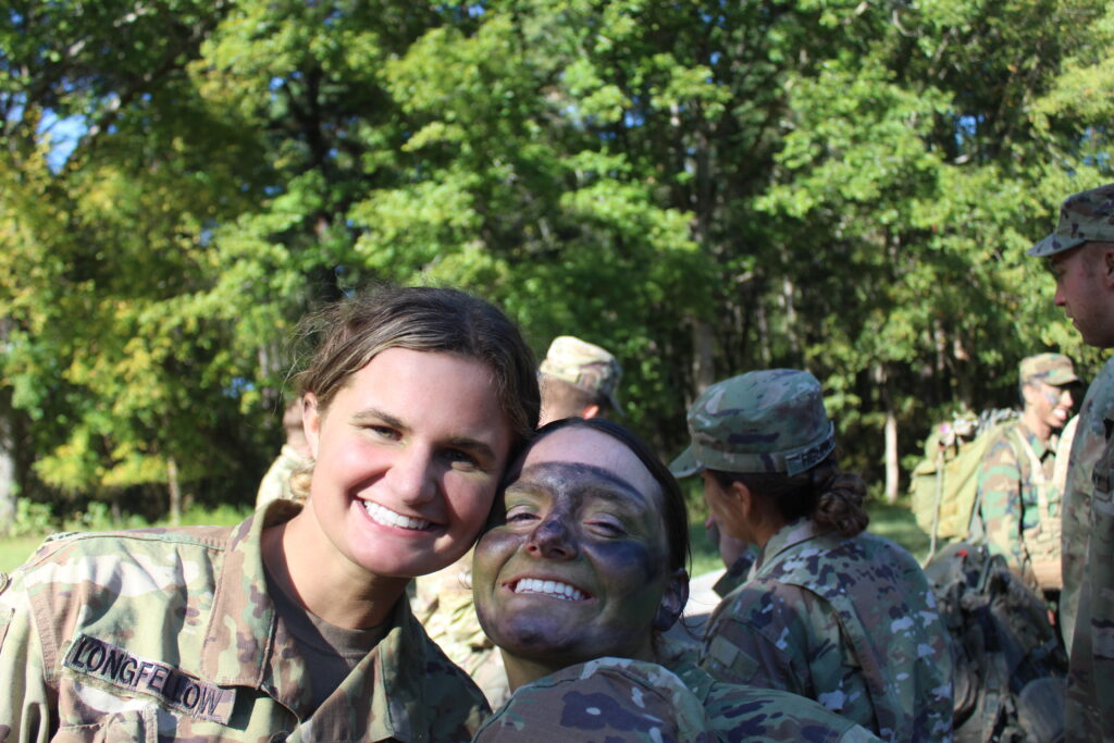 Two cadets pose for a photo, one in camouflage face paint 