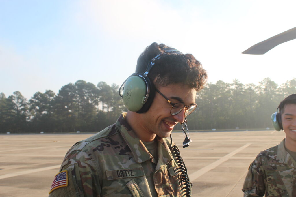 A cadet wearing headphones and a microphone practices using a radio 