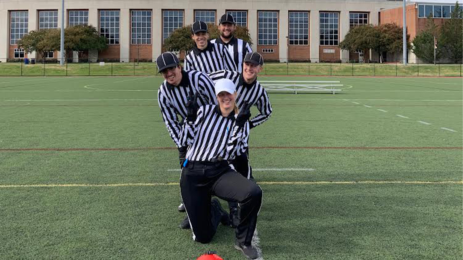 Hannah Williams and other students in referee uniforms lined up on a grassy field