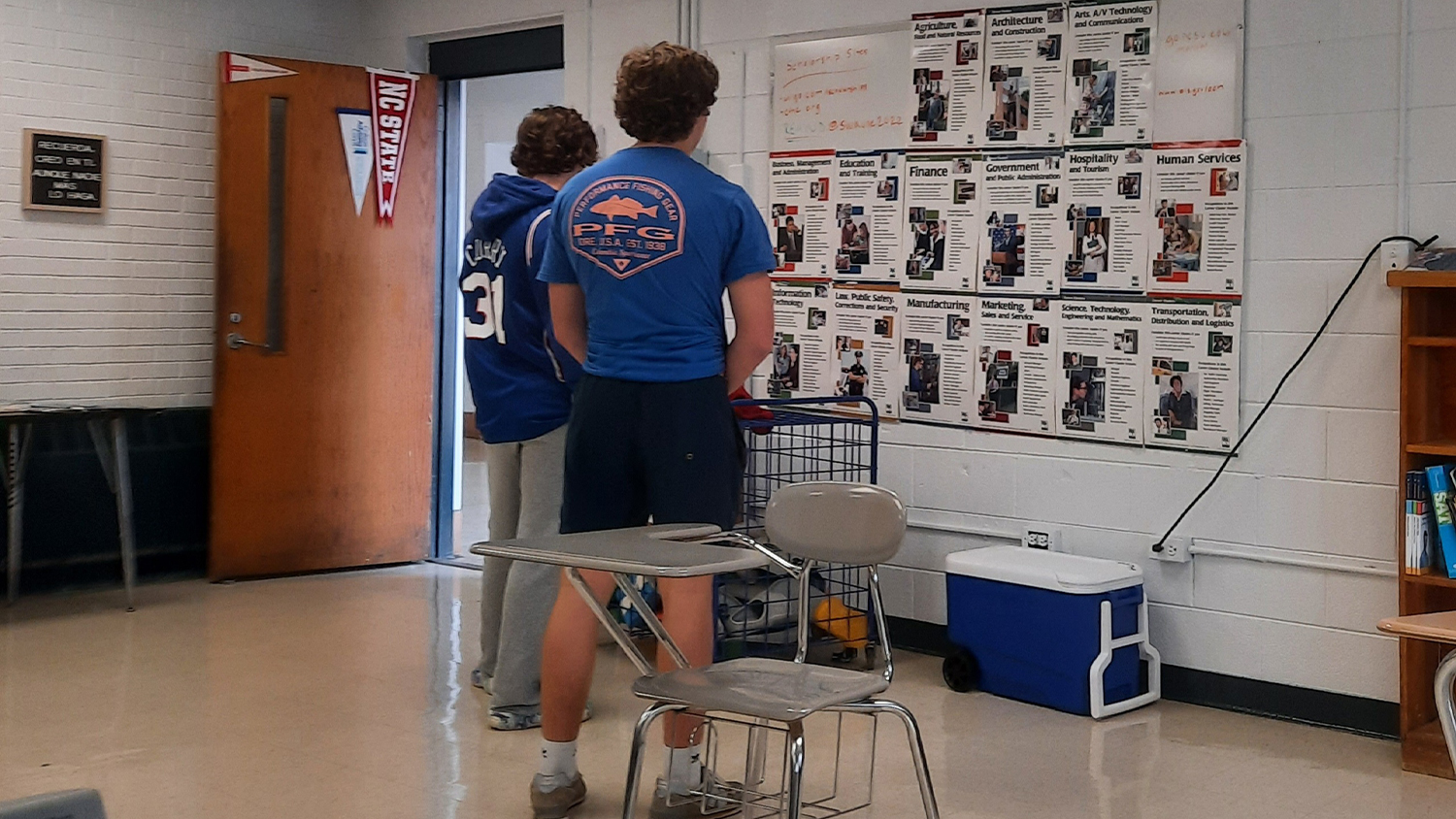 Two students look at a bulletin board in a classroom