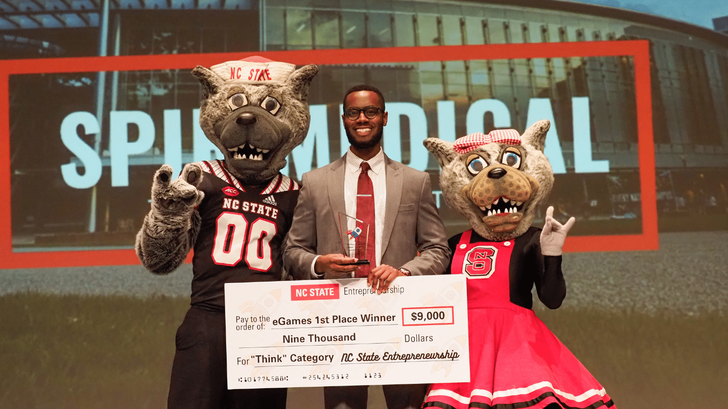 Mr. and Mrs. Wuf pose with the first-place winner of the eGames, who is holding a giant check