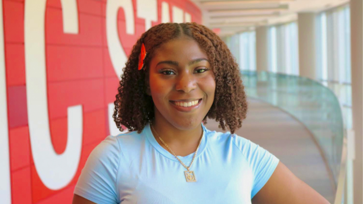 London Tolson in front of a red wall with the NC State logo on it
