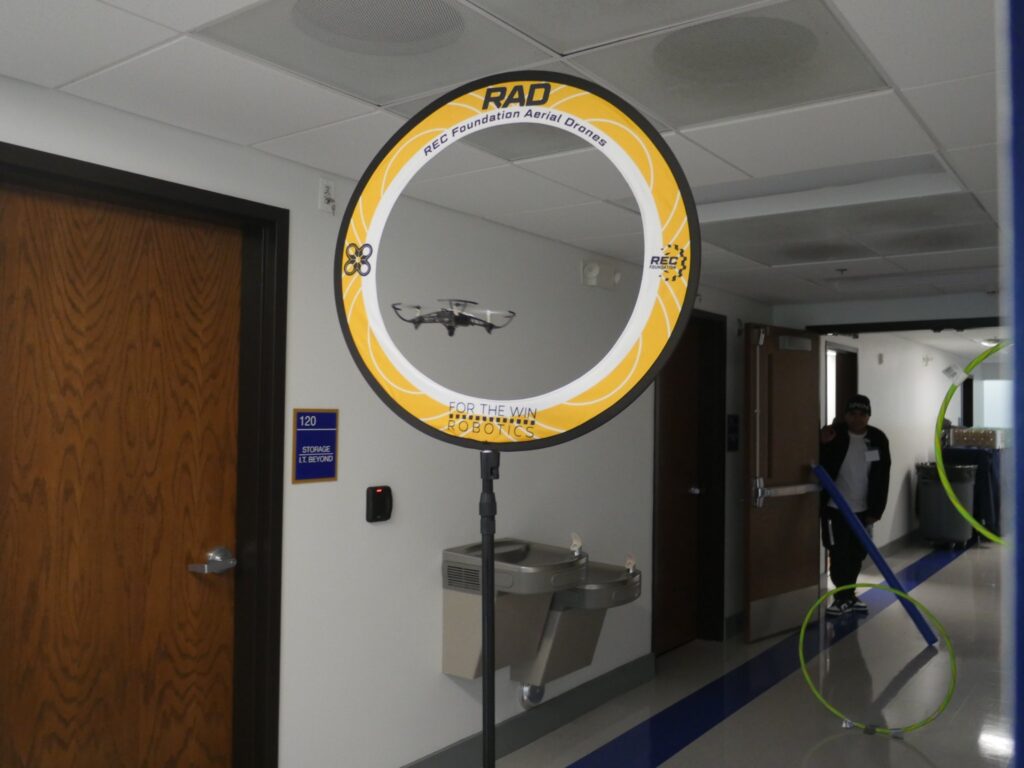 A drone flies through a yellow mounted ring in a hallway