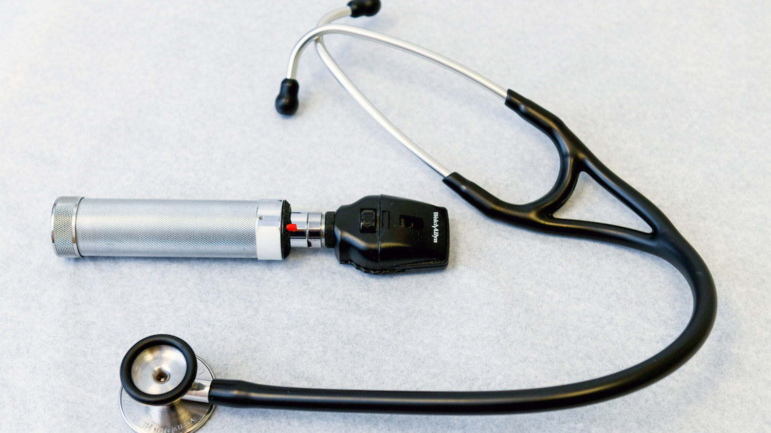 A stethoscope and thermometer on a white table