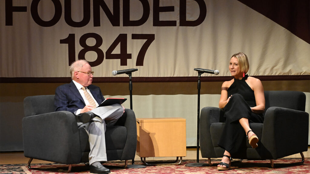 Megan Albidrez sitting in a chair on stage across from another man who is also seated and interviewing her
