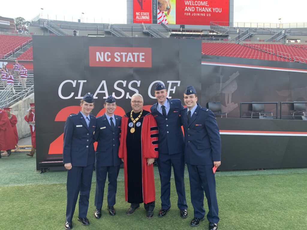 Hannah Fletcher and her fellow cadets from NC State pose with Chancellor Randy Woodson after her graduation ceremony