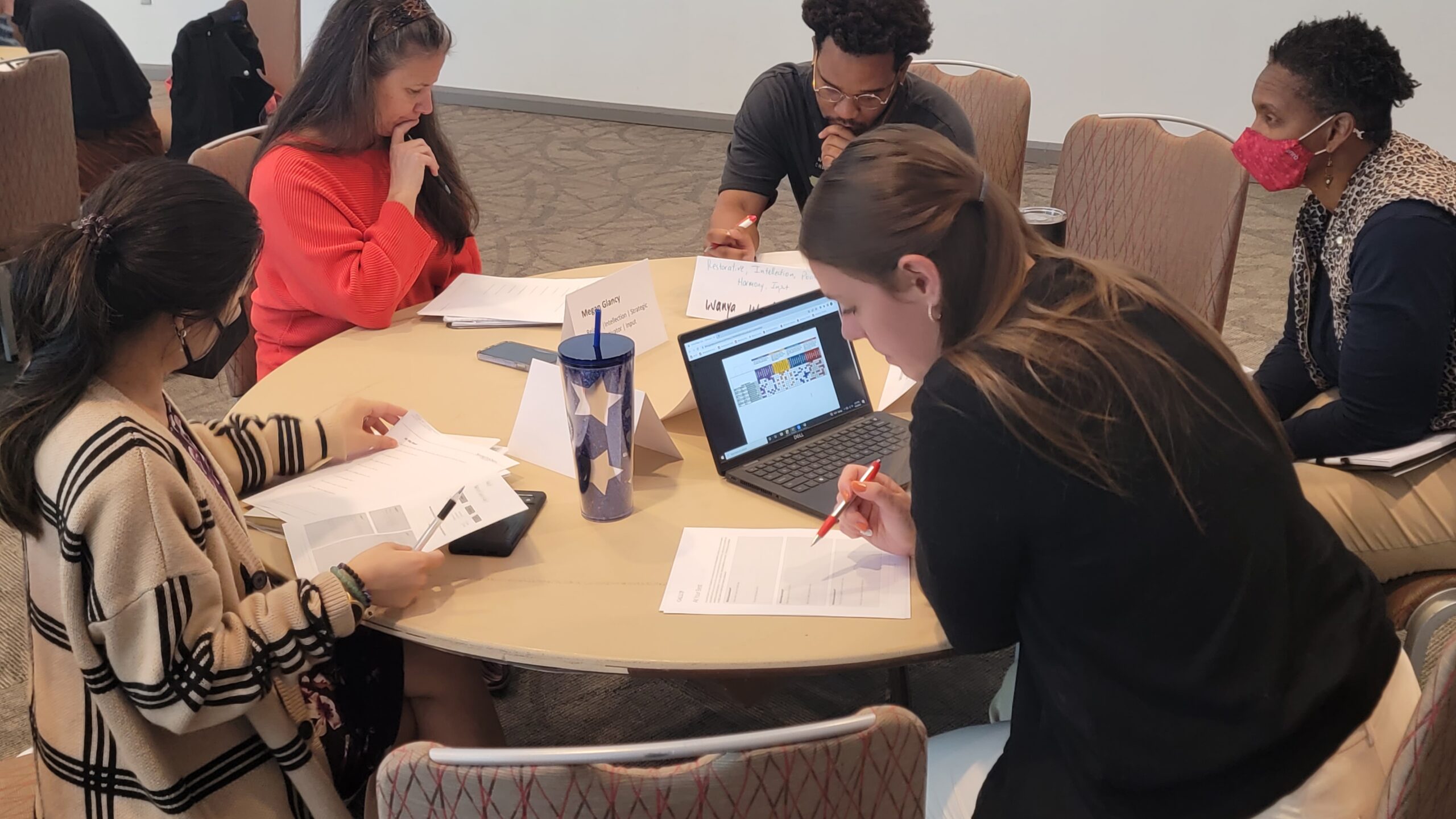 A group of people sit around a table and work on an assignment
