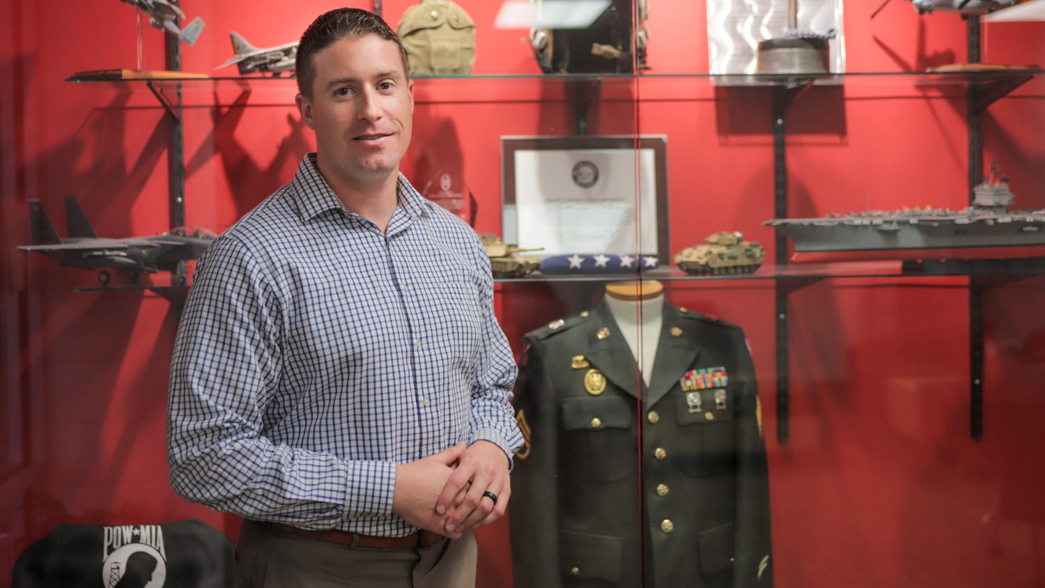 Nick Drake in front of a display case in the Military and Veteran Services office at NC State