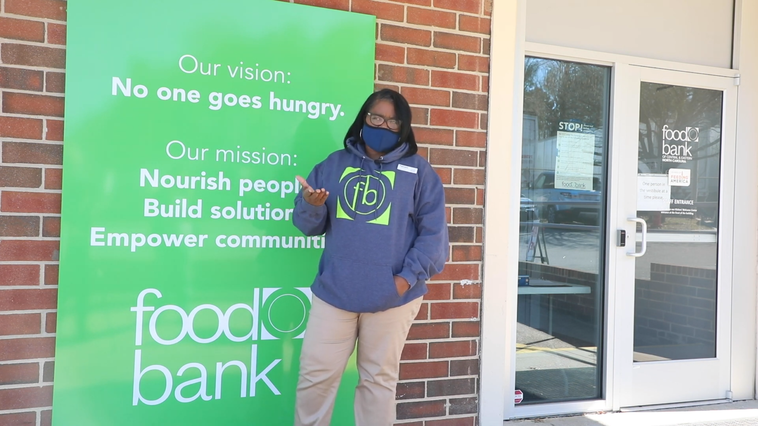 A spokesperson for the Food Bank of Central & Eastern North Carolina stands in front of a green sign for the organization