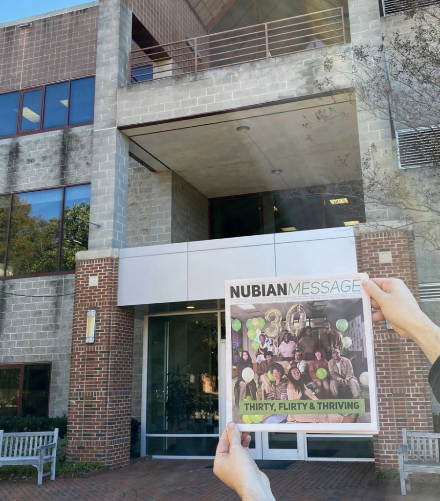 Hands hold up a copy of the Nubian Message in front of Witherspoon Student Center
