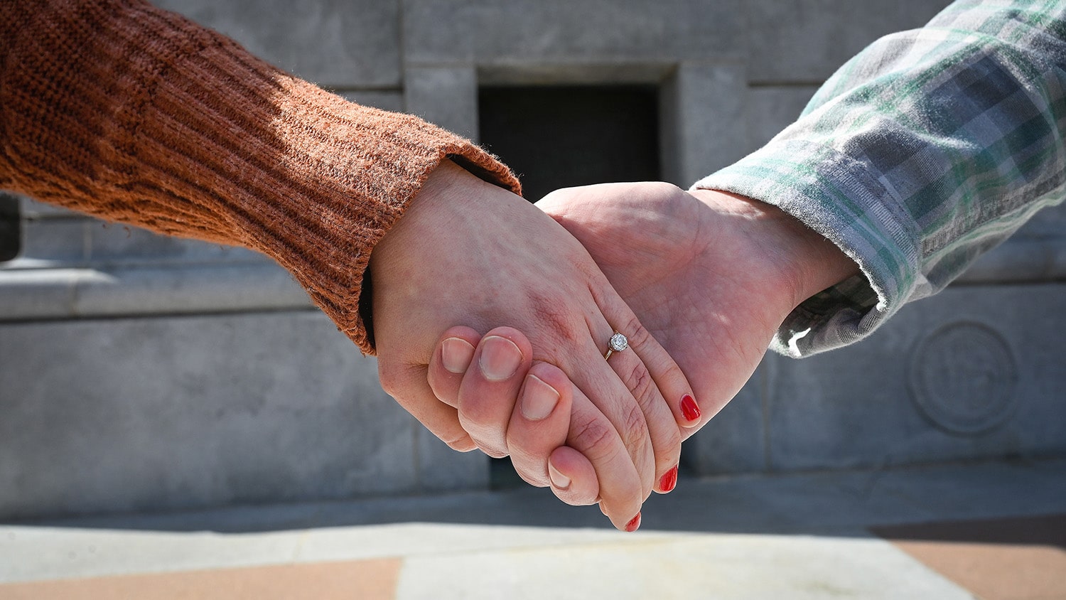 Two people hold hands in front of the Memorial Belltower
