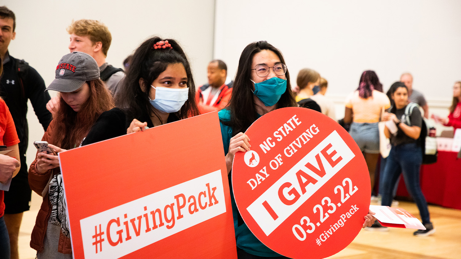 Two students hold signs for #GivingPack