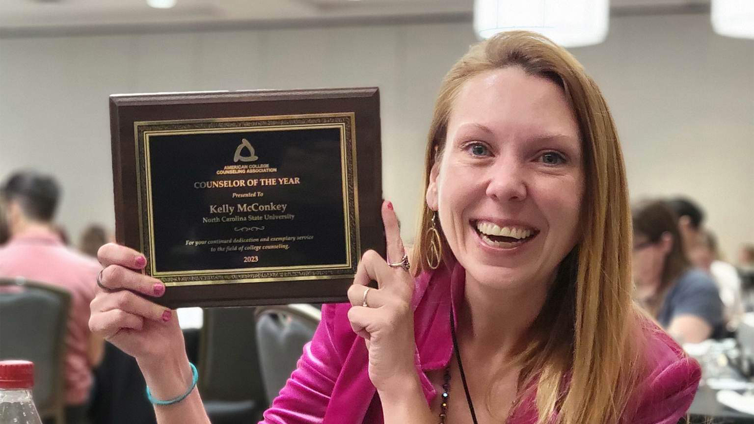 Kelly McConkey holds up a plaque recognizing her as national counselor of the year