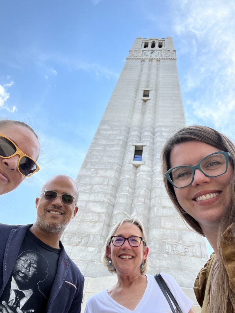 A selfie of DBR with three people in front of the NC State Memorial Belltower
