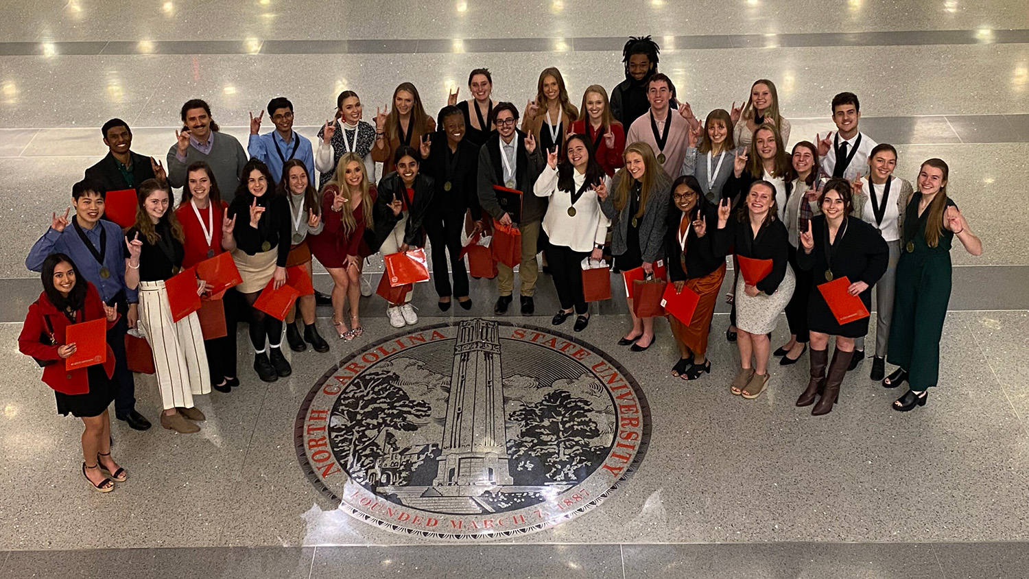 University Honors Program and University Scholars Program graduates stand around the University seal in the lobby of Talley Student Center after the Honors Program Recognition Ceremony on Tuesday, Dec. 12