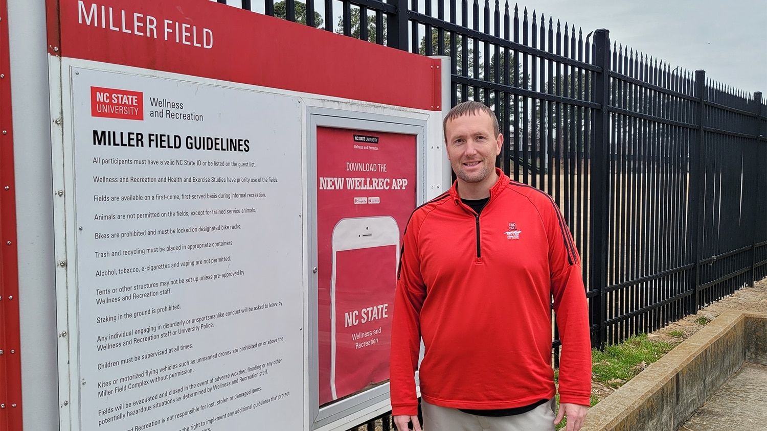 Ben Strunk stands next to a large sign for Miller Fields