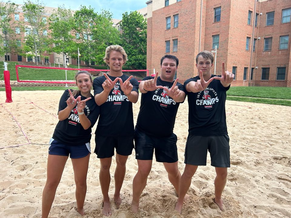 intramural sand volleyball team holding up W symbols with their hands