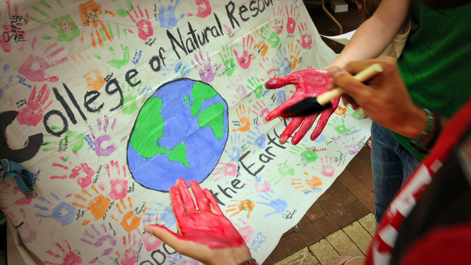 students painting hands to put on a poster about celebrating Earth Day
