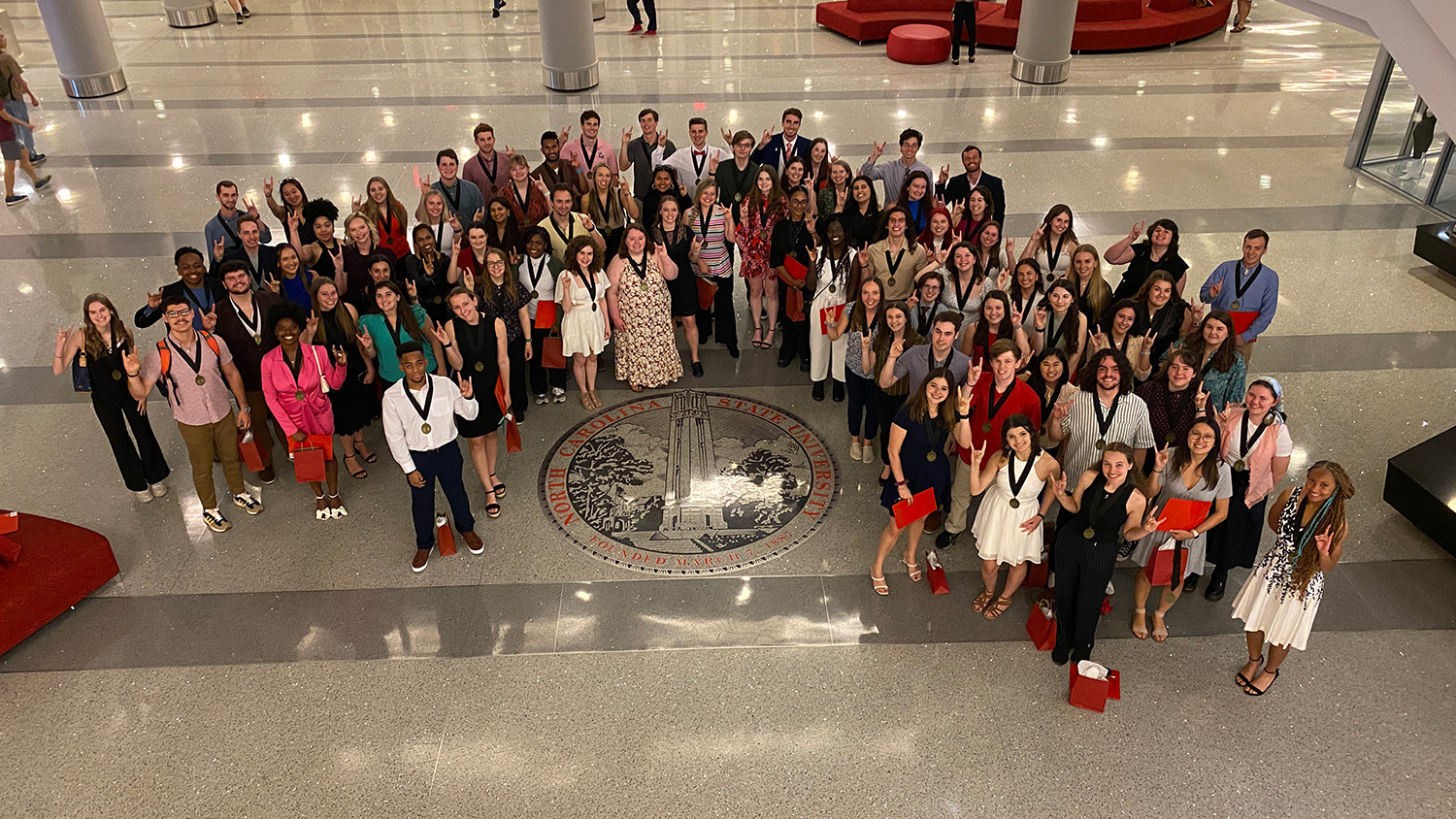 University Scholars Program graduating seniors gathered around the NC State seal on the night of their Senior Recognition Ceremony for one final group picture together.