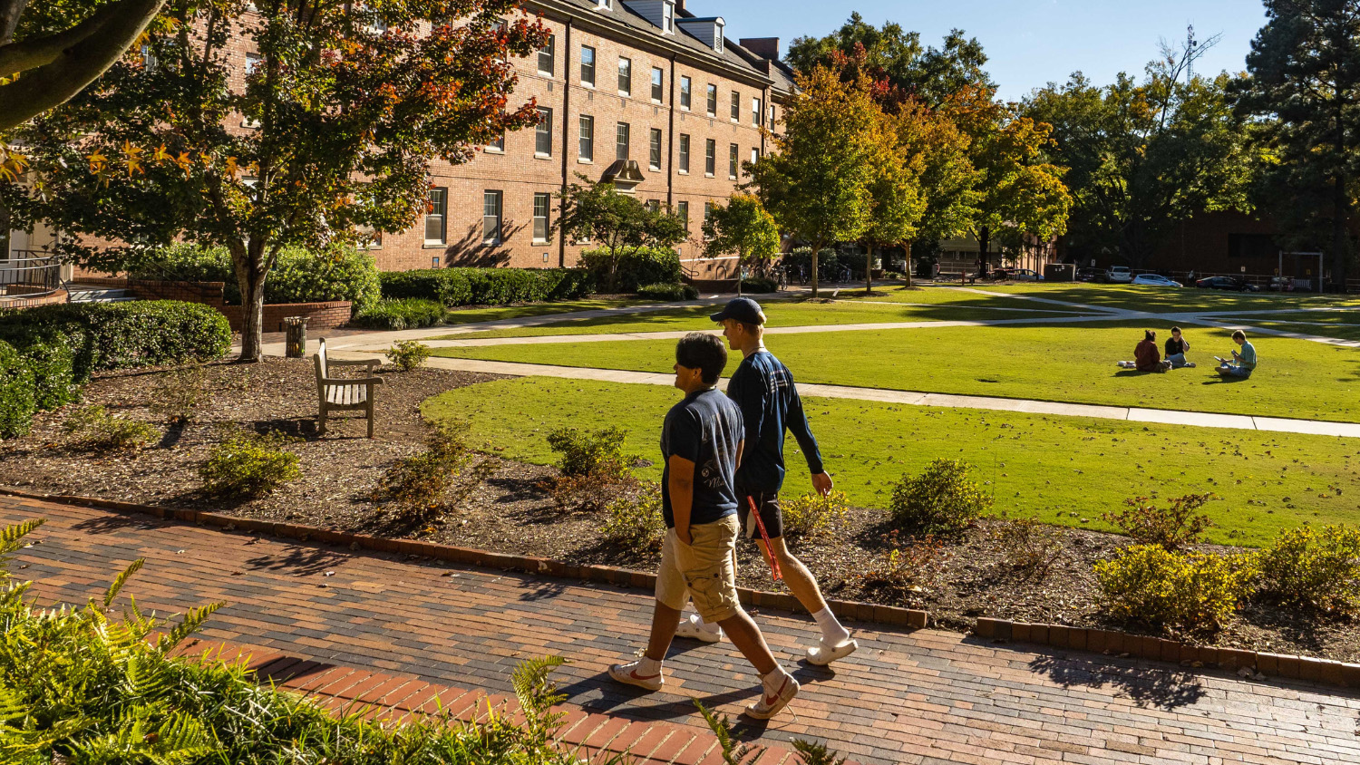 Students walk on a sunlit part of campus.