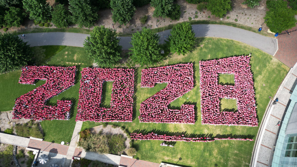 New NC State students in the class of 2028 arrange themselves in the shape of the numbers for a photo on the Talley Student Union lawn.