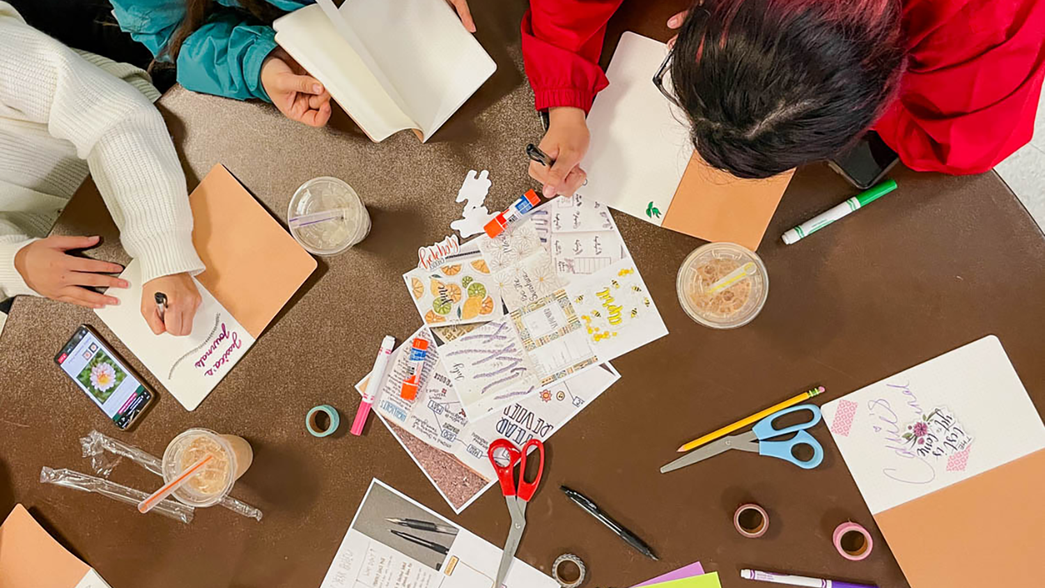 Students go over study materials on a coffee table.