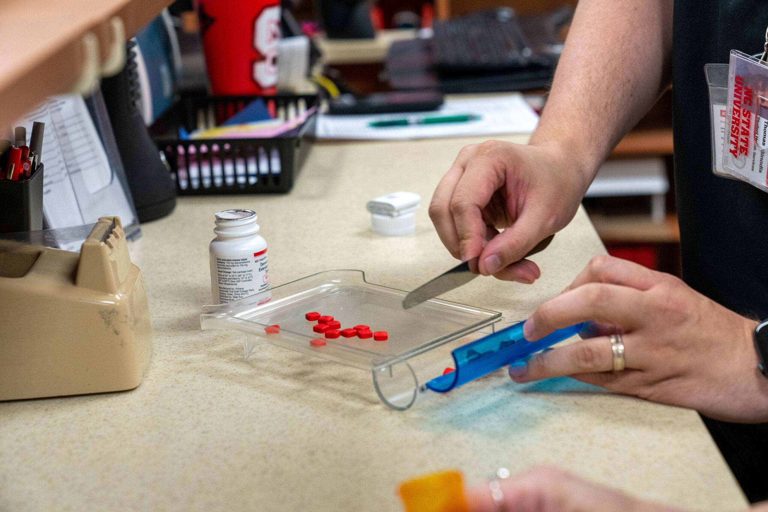 A pharmacist measures pills into a container.