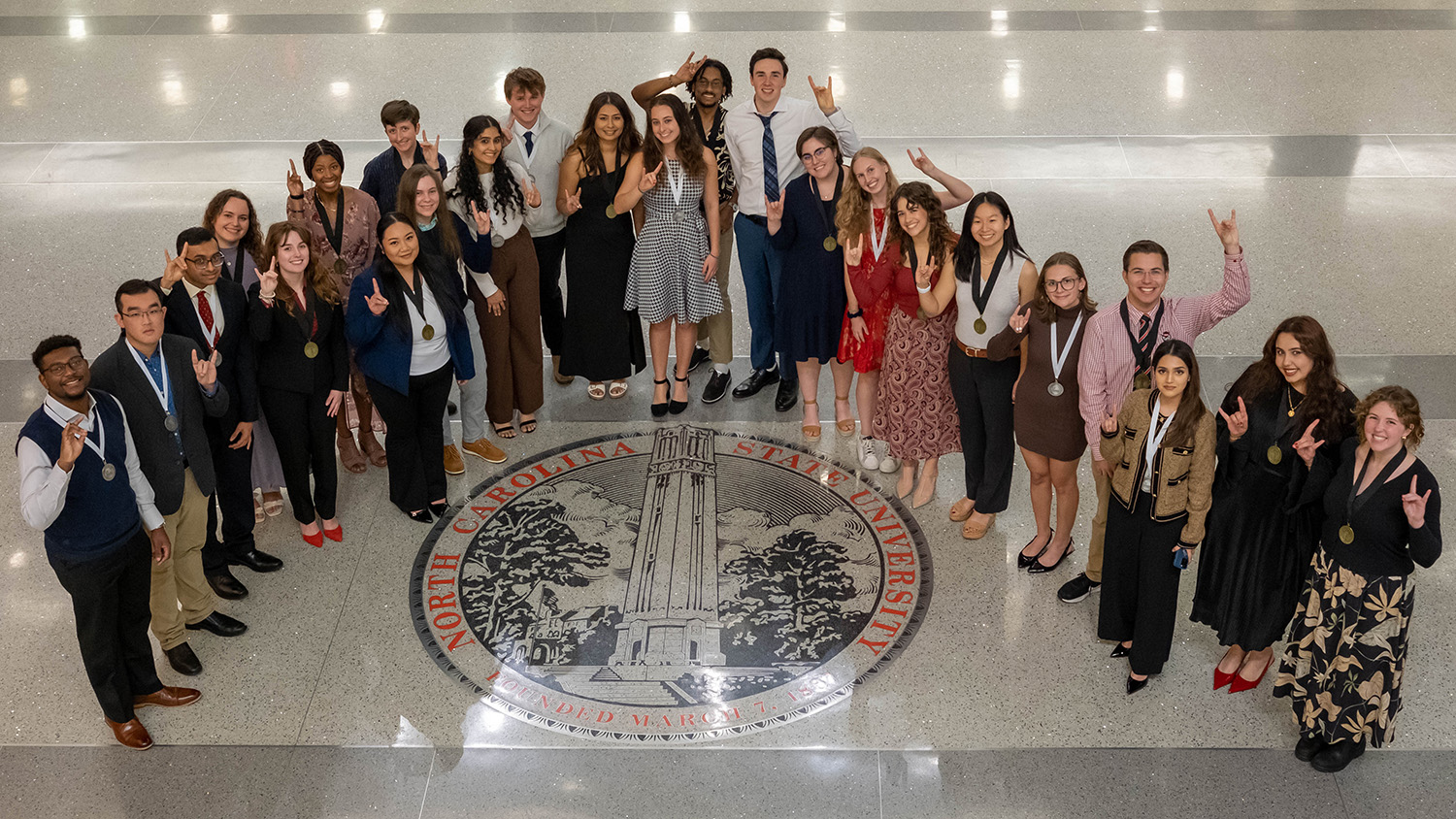 University Honors Program and University Scholars Program Fall 2024 graduates stand around the University seal in Talley Student Union for a traditional group photo after their Senior Recognition Ceremony.