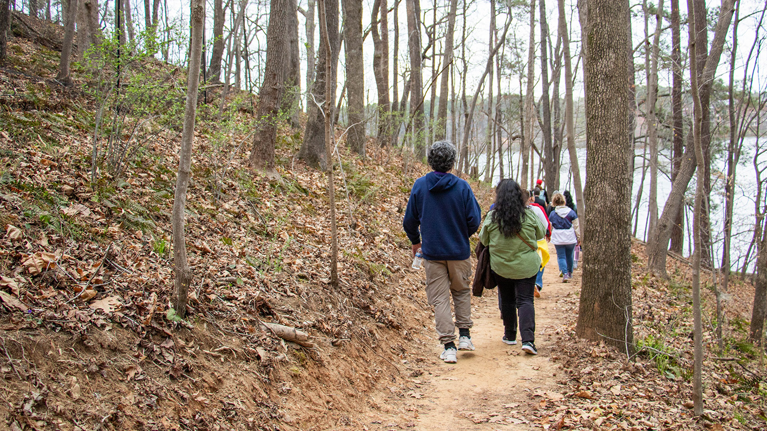 Students hike through the woods at Lake Raleigh.