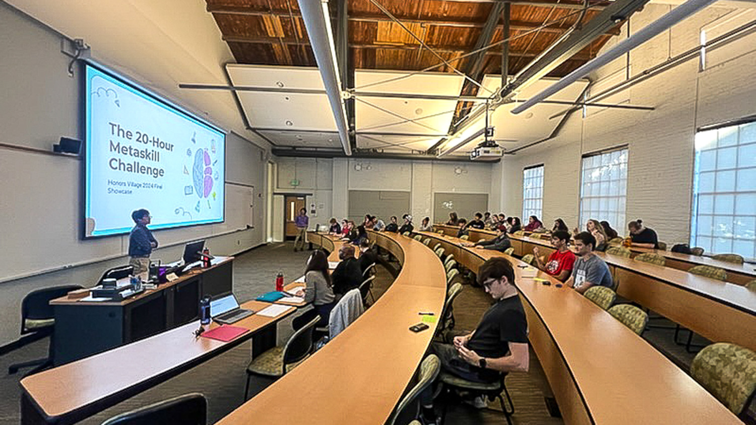 Presentation with "The 20-Hour Metaskill Challenge at the front of a lecture hall with students listening.