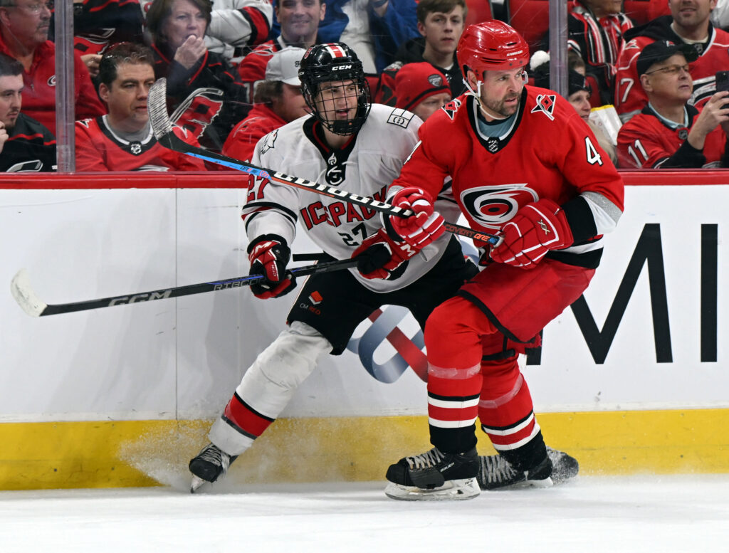 Nick Shook of NC State Icepack and Hurricanes alumnus Aaron Ward battle for possession.